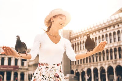 Woman with arms raised against city in background