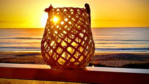 Metallic structure on beach against sky during sunset