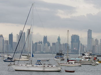 Sailboats in sea against cloudy sky