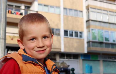 Portrait of a cute blond boy on the background of a residential building. smiling six year old boy.