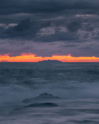 Scenic view of sea against dramatic sky during sunset