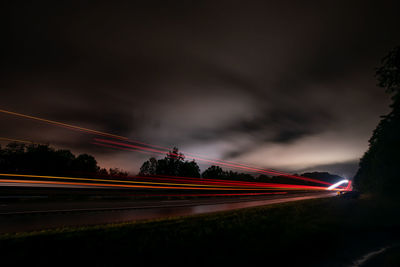 Light trails on road against sky at night