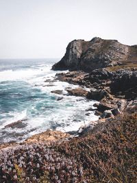 Rock formations by sea against clear sky