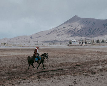 Man riding motorcycle on desert against sky