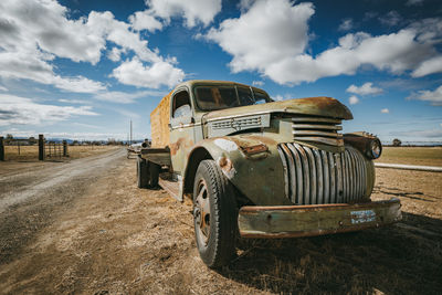 Abandoned car on field against sky