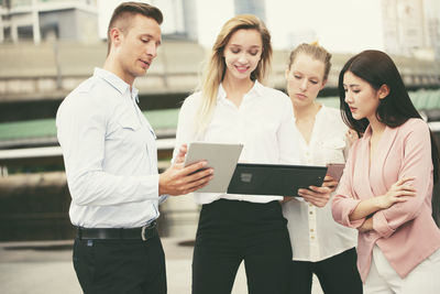 Friends looking away while standing on mobile phone