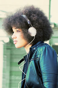 Close-up portrait of young woman listening music through headphones