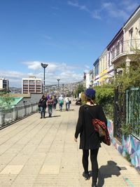 Rear view of people walking on footpath in city