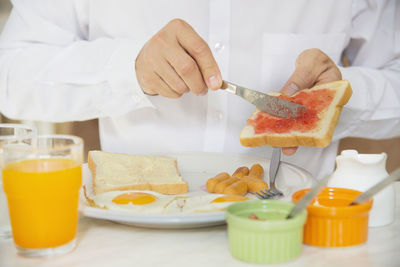 Midsection of man applying jam on bread