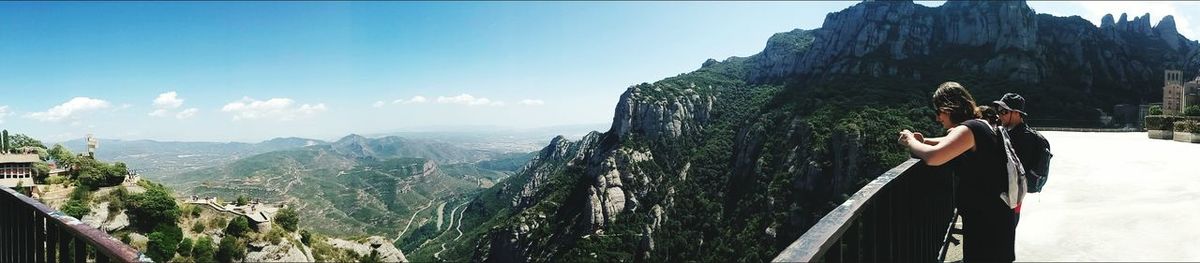 People standing at observation point by mountains against sky