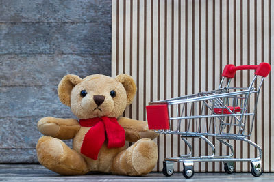 Close-up of stuffed toy by shopping cart against wall