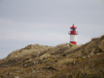 Lighthouse on field against sky