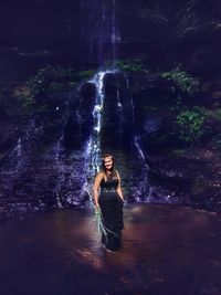 Portrait of girl standing against waterfall in forest