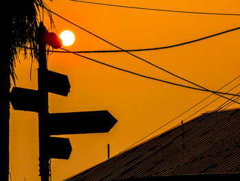 Power lines against sky at sunset