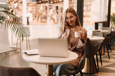 A millennial business woman works and studies online using a mobile phone and technology in a cafe