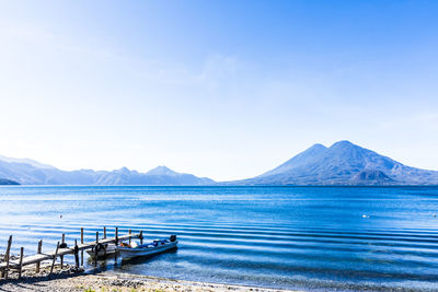 Scenic view of sea and mountains against blue sky