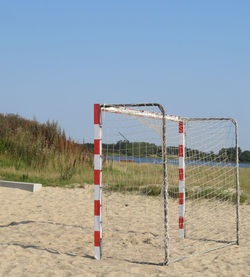 Soccer goal on sand against clear blue sky