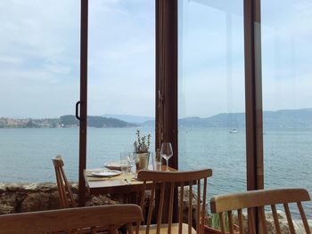 Chairs and tables by sea against sky