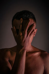 Portrait of shirtless man against black background