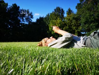 Woman using phone while lying on field