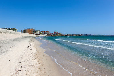 Scenic view of beach against clear blue sky