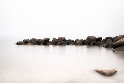 Rocks by sea against clear sky