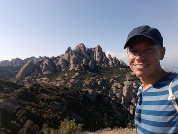 Portrait of man smiling while standing against mountains