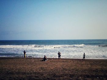 Silhouette people standing on beach against clear sky