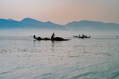 Silhouette of fishermen against sky during sunset