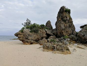 Rock formation on beach against sky