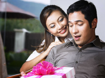 Smiling mid adult woman looking at man with gift at home