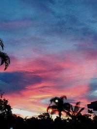 Low angle view of silhouette trees against dramatic sky