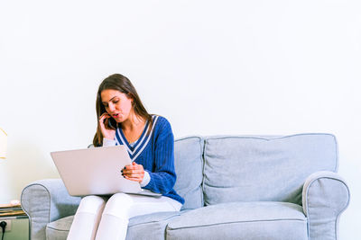 Young woman using mobile phone while sitting on sofa