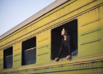 Low angle view of woman looking through window of abandoned train