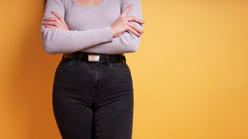 Midsection of woman standing against yellow background