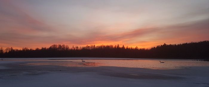 Scenic view of lake against orange sky during winter