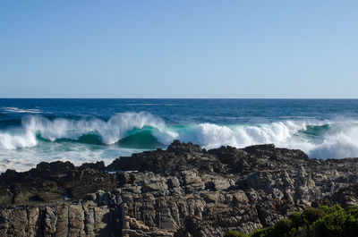 Rock formations at sea shore against clear sky