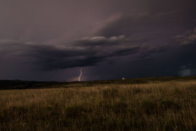 Scenic view of field against storm clouds