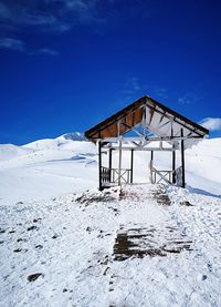 Lifeguard hut on snow covered mountain against sky