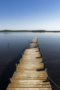 Wooden jetty on pier over lake against sky