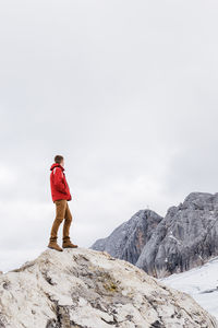 Young millennial man enjoys the views of the alps standing on glacier