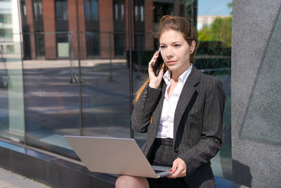 Business woman working on street. young woman is sitting on bench with laptop