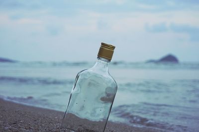 Close-up of bottle on beach against sky