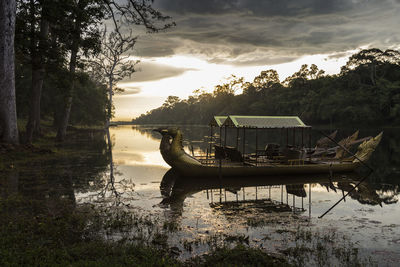 Boats in lake against sky during sunset