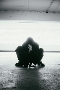 Side view of man sitting on floor