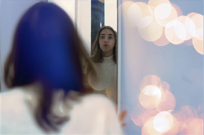 Portrait of young woman standing by window