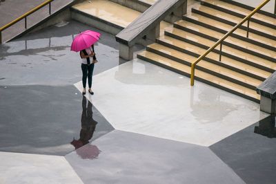 High angle view of woman under umbrella standing on footpath