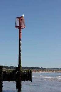 Wooden posts on sea against clear sky