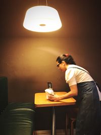 Young woman using mobile phone in illuminated room