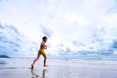 Full length of a boy running on beach against sky